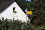 Eingangsbereich mit Hinweisschild und Hausfassade