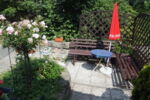 Terrasse mit Sitzbank und rotem Sonnenschirm